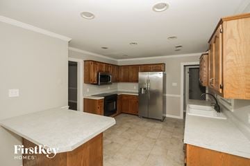 Collierville house for rent - a kitchen with wooden cabinets and a stainless steel refrigerator