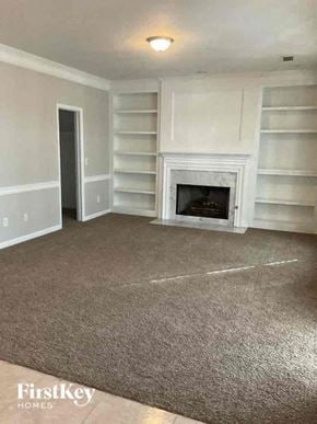Jonesboro house for rent - an empty living room with a fireplace and white shelves