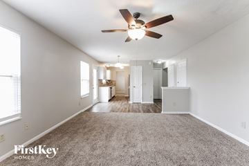 Indianapolis house for rent - a spacious living room with carpet and a ceiling fan