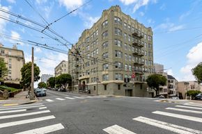 San Francisco apartment for rent - A street view of a city intersection with a large building in the background.