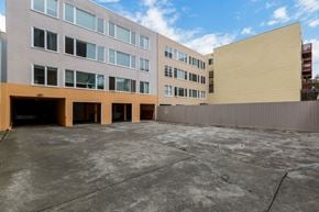 San Francisco apartment for rent - A large, empty parking lot in front of a building with a yellow wall.