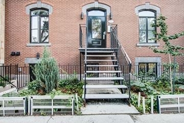 Montréal apartment for rent - A red brick house with a black door and a metal railing.