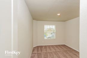 San Antonio house for rent - A room with a carpeted floor and a window showing a house and trees outside.