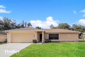 Deltona house for rent - a beige house with a lawn and a driveway