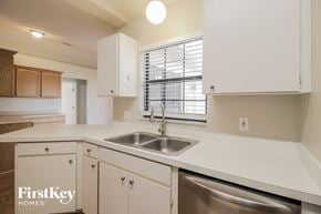 Deltona house for rent - a kitchen with white cabinets and a sink and a window