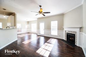 Whitsett house for rent - A spacious living room with a fireplace and a ceiling fan.
