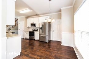 Whitsett house for rent - A kitchen with a refrigerator, microwave, oven, and sink.