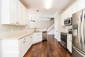 Whitsett house for rent - A kitchen with white cabinets and a wooden floor.