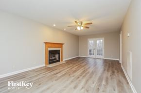 Clarksville house for rent - A spacious room with a fireplace and a ceiling fan.