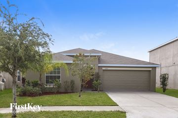 Wimauma house for rent - a beige house with a driveway and trees