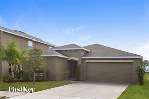 Wimauma house for rent - a beige house with a driveway and a garage door