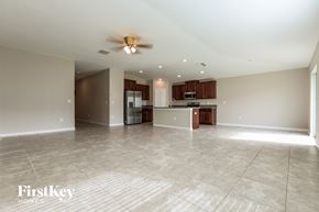 Wimauma house for rent - an empty living room and kitchen with a ceiling fan