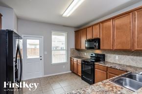 San Antonio house for rent - A kitchen with wooden cabinets and a black stove top oven.