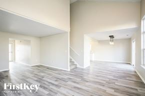 Noblesville house for rent - A spacious room with wooden flooring and a staircase in the background.