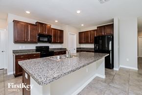 Wimauma house for rent - a kitchen with granite counter tops and dark wood cabinets