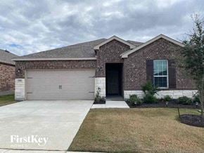 Forney house for rent - A brick house with a garage door and a tree in front.