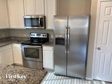 Forney house for rent - A kitchen with a stainless steel refrigerator and microwave above an oven.