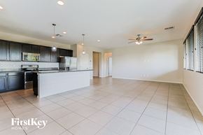 Queen Creek house for rent - an empty kitchen and living room with white tile floors and black cabinets