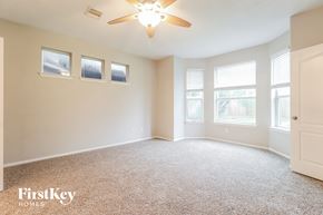 Kingwood house for rent - A spacious room with a carpeted floor, a ceiling fan, and three windows.