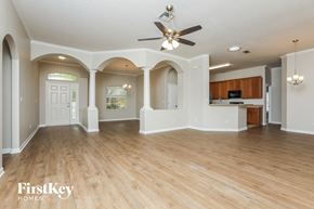Leesburg house for rent - an open kitchen and living room with wood flooring and a ceiling fan