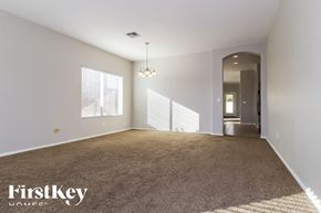Avondale house for rent - A spacious room with a carpeted floor and a chandelier hanging from the ceiling.