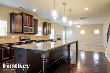 Covington house for rent - a kitchen with a large island with granite counter tops and dark wood cabinets