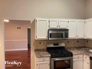 Dallas house for rent - A kitchen with white cabinets and a black stove top oven.