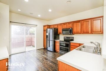 Peyton house for rent - a kitchen with wooden cabinets and a black refrigerator