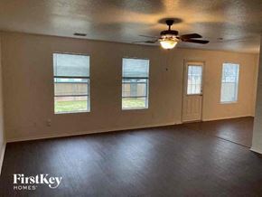 Fort Worth house for rent - an empty living room with a ceiling fan and three windows