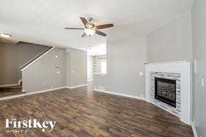 Commerce City house for rent - A spacious room with a fireplace and a ceiling fan.