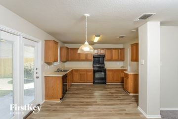 San Antonio house for rent - a kitchen with wooden cabinets and black appliances and a sliding glass door