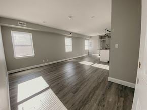 Tonawanda apartment for rent - the living room and kitchen of a new home with wood floors and grey walls