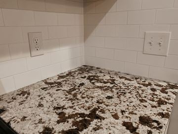 Tonawanda apartment for rent - a kitchen with a granite counter top and white tile walls