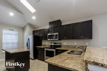 Valrico house for rent - a kitchen with granite counter tops and black cabinets and stainless steel appliances