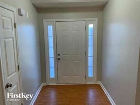 Lawrenceville house for rent - A white door with a glass panel is in the middle of a hallway with wood floors and white walls.