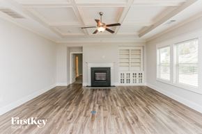 Gainesville house for rent - A spacious room with a fireplace and a ceiling fan.