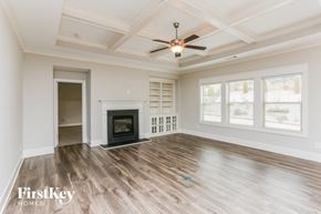 Gainesville house for rent - A spacious room with a fireplace and a ceiling fan.