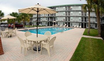 Kissimmee apartment for rent - a swimming pool with a table and chairs in front of a building
