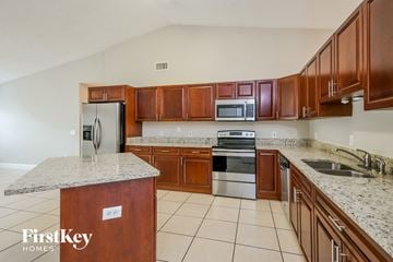 Kissimmee house for rent - a kitchen with wooden cabinets and stainless steel appliances and granite counter tops