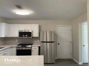 Snellville house for rent - a kitchen with white cabinets and a stainless steel refrigerator