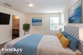 Jacksonville house for rent - A bedroom with a bed, a plant, and two paintings on the wall.
