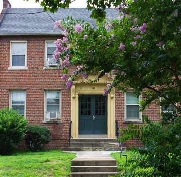 Washington apartment for rent - A house with a green lawn and a tree with purple flowers in front.
