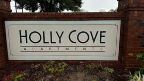 Moultrie apartment for rent - A sign that says "Holly Cove Apartments" is displayed in front of a brick wall.