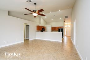 Cape Coral house for rent - A spacious room with a ceiling fan and a kitchen area in the background.