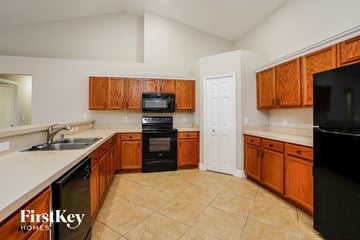 Cape Coral house for rent - A kitchen with wooden cabinets and black appliances.