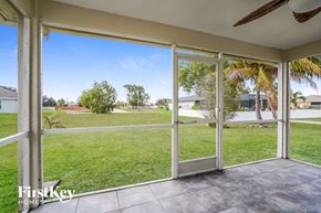 Cape Coral house for rent - A patio with sliding glass doors opens to a grassy backyard.