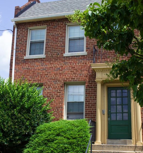 Washington apartment for rent - A red brick house with a green door and a window covered with blinds.