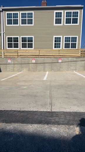 Washington apartment for rent - A grey building with a parking lot in front.