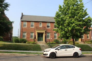 Washington apartment for rent - A white car is parked in front of a red brick house.