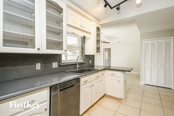 Kissimmee house for rent - a kitchen with white cabinets and a sink and a window